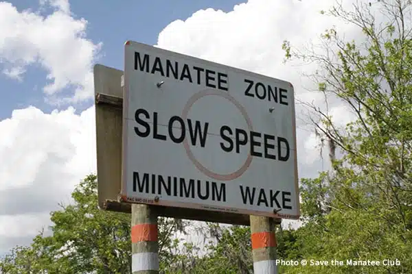 A regulatory signed with an orange circle in the middle and the text, "Manatee Zone, Slow Speed, Minimum Wake" to indicate the boating speed requirement in the area.