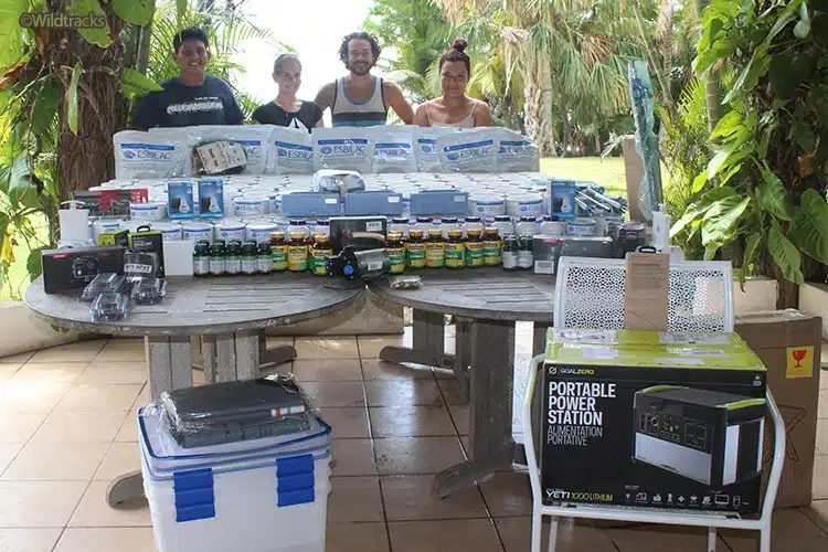 Four members of the Wildtracks team pictured with a variety of items, which were purchased from Save the Manatee Club's wish list. The items include a portable power station, vitamins, thermometers, several bottles of vitamins, and pounds of milk replacement formula.