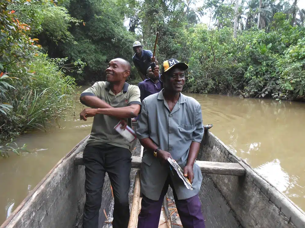 Four men in a boat on the Kwa Iboe River, monitoring the environment.