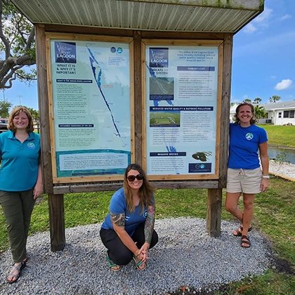 SMC staff members Tiare (left) and Meghan (right), pose with City of Satellite Beach Staff Biologist Jennifer White (center) in front of the new kiosk installed at DeSoto Canal. Photo by Save the Manatee Club.