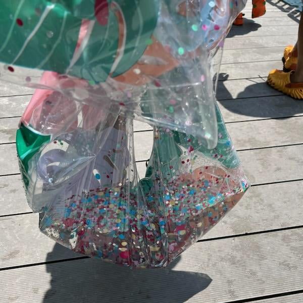 An inner tube full of small plastic glitter after it's failed, carefully held to prevent the contents from spilling out onto the boardwalk at Blue Spring State Park.