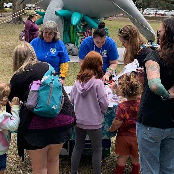 SMC volunteers Heather (left) and Sammi make manatee puppets with children at the Blue Spring Manatee Festival.