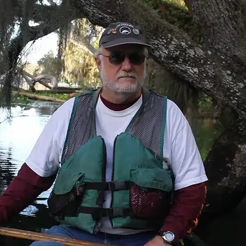 A photo of Wayne Hartley on the researcher canoe wearing a dark green lifejacket.